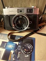 Front view of Konica Auto S2 camera showing Hexanon lens, lens markings and attached brown leather strap.