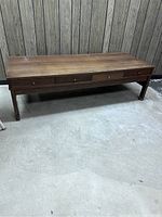 Front view of the rectangular wooden coffee table with four drawers and tray tables inside.