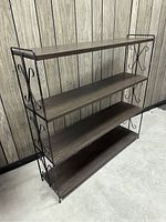 Full angled view showing the entire shelf unit with scrolled metal sides and four faux wood grain shelves in dark brown.