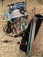 Photo showing Tittall tripod folded next to a black carrying case, a Pistol Grip Task Light in its box, Philips Director 60 bulb box, a power cord and switch, and a metal reflector bowl with glass cover.