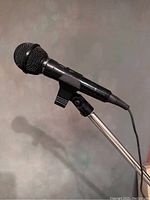 Close-up of the DALCODYNAMIC IMP-600 wired microphone mounted on the stand, showing black body and mesh grille.