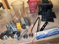 Overall view of photographic darkroom equipment including glass cylinders, metal tank parts, Kodak Anti-Fogg boxes, black plastic components, and thermometers