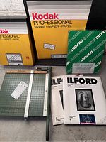 Photo showing Premier paper cutter, Kodak professional photographic paper, Ilford photographic papers, and DuPont Varicolour photographic paper on display.