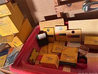Photo showing various Kodak boxes with safelight filters, lamp kits, and other small photographic darkroom accessories neatly arranged.