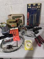Overview of all tools including Black + Decker skill saw, tape rolls, file set, drills, Rawl hole saw attachment, strap wrench.