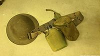 Photo showing the helmet, canvas utility belt with canteen and pouch attachments on a surface
