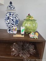 Photo showing all 5 home decor items on wooden shelf including ceramic jars, shot glasses, figurine, and glass bowl
