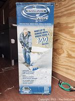 Box front view showing Snowjoe Plus electric snow thrower and main features including 300 lbs/min snow removal capability.