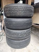 Four tires stacked showing tire tread condition and size markings.