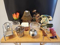 Photo showing overall view of 16 assorted home decor items on wooden surface against black backdrop.