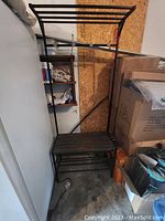 Full view of metal framed hall tree showing bench seat and supporting frame.