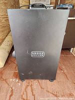Front view of black Smoke Hollow electric smoker unit with logo visible on door.