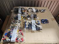 Multiple sealed bags of LEGO pieces arranged on a surface, with some bags clearly numbered for sorting purposes.