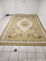 Full view of the rectangular area rug on tiled floor showing overall design and condition.