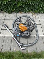Canister vacuum unit with hose and wand arranged on paved surface