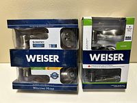Photo showing two boxed Weiser door hardware sets, one marked as passage and the other as a lock set.