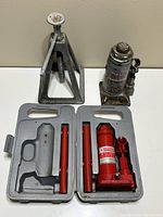 Photo of manual screw-type jack, Pro-Lift 6-ton bottle jack, and red 2-ton bottle jack in open case with handles