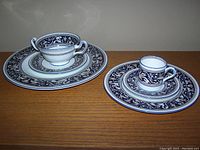 Wide shot showing stacked plates with demitasse coffee cup and handled soup cup illustrating pattern and size variety