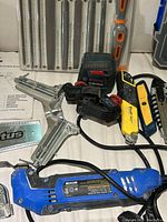 Bosch laser level, several box cutters, metal clamps, and small tools laid out