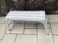 Front and side view showing aluminum slat top and four-legged frame with locking mechanism.