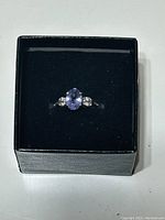 Ring in black display box showing top view with tanzanite and diamond arrangement
