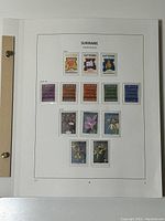 Page showing Suriname stamps dated 1975-1976 with floral and thematic designs in bright colors, all mint and in protective covers.