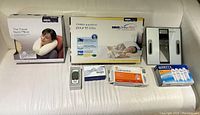 Lot overview showing all included health and wellness items arranged on a white couch, including neck pillows, weight scale, pain relief products, filters, and crutches.