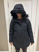 Front view of black Eddie Bauer women's winter jacket with hood up showing faux fur trim and front closure