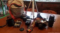 Full lot on table: camera bag, camera body, lenses, flash, tripod