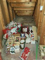 Photo of Christmas decorations under basement stairs including hand knitted stocking, boxes of ornaments, and tree angel topper