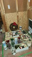Group view of pinecone wreath, glass vases and boxed ornaments on basement floor