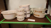 Photo showing the full set of dishes arranged on a shelf including Fire-King mixing bowls, Fire-King baking dishes, and CorningWare baking dishes.