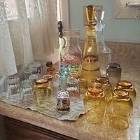 Overview of the decanters, coloured glasses, and shot glasses arranged on a towel on the countertop