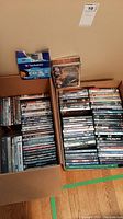 Two boxes filled with assorted DVDs stacked vertically, with some DVD titles visible