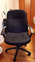 Front view of black office chair showing padded seat, backrest, armrests, and wheeled base.