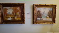 Two framed paintings hanging side by side on wall