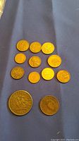 View of eleven assorted pennies including 1857 Bank of Upper Canada penny and others laid out on blue cloth