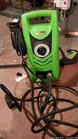 Full view of the green Power It! PW 1600 pressure washer showing the front control dial, hoses, and wand.