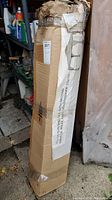 Photo of the boxed sun shelter standing upright in storage, shows label and cardboard wear.