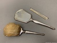 Overall top view of mirror, brush, and comb on grey background