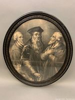 Full view of the oval framed etching depicting three men, showing frame wear.
