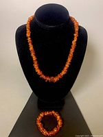 Full view of amber nugget bead necklace on display stand with stretch bracelet below.