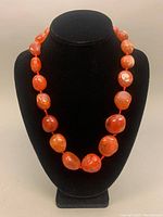 Front view of the hand knotted agate stone necklace displayed on a black bust stand showing uniform stones with warm orange hues.