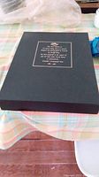 Black slipcase for the book with gold embossed text about the first edition and author.