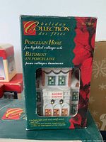 Close-up photo of porcelain Railway Station in its original box from the Holiday Collection, showing detailed architectural design and label.