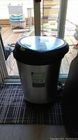 Full view of Type A stainless steel and plastic garbage can showing size and condition by glass door.