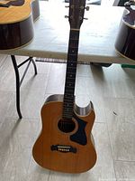Front view of Magnum Marquis series acoustic guitar model MS-300 with visible wear and damage, natural wood finish with black pickguard and cutaway body shape.