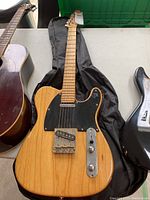 Full front view of guitar laid on gig bag, showing body shape, pickguard, pickups and bridge.
