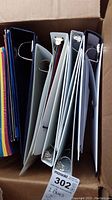 View looking down into a box showing multiple ring binders in white and black with papers inside