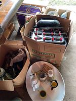 Carton with metal muffin tins, other kitchenware items including mugs, strainers, and decorative bowls.